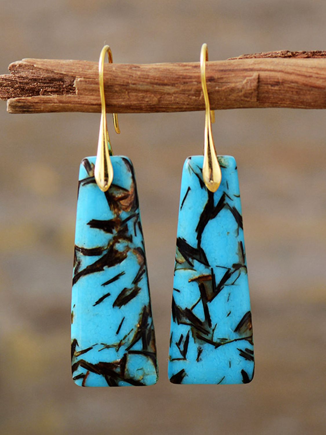 Geometric stone drop earrings in sky blue with black inclusions and gold hooks.
