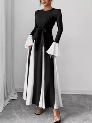 Black maxi dress with tie waist and dramatic flare sleeves, featuring contrasting white panels.