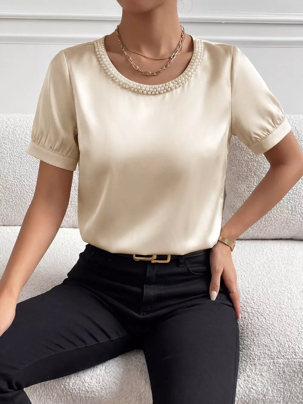 Pearl-trimmed satin bodysuit with short puff sleeves and a round neckline.