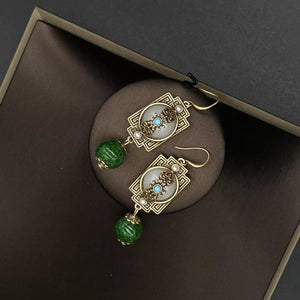 Vintage gold-plated dangle earrings with dark green beads and white stone accents.