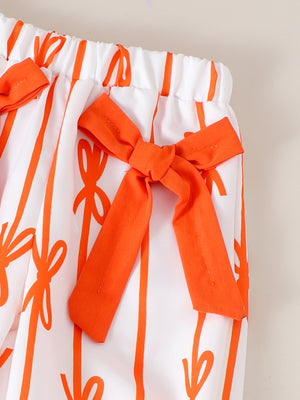Baby pants with white cotton and orange bow pattern, featuring orange bows at the waist.