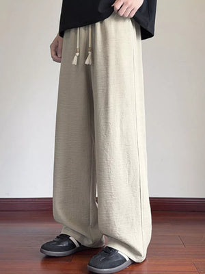 Cream wide-leg drawstring sweatpants with tassel detail and relaxed fit.