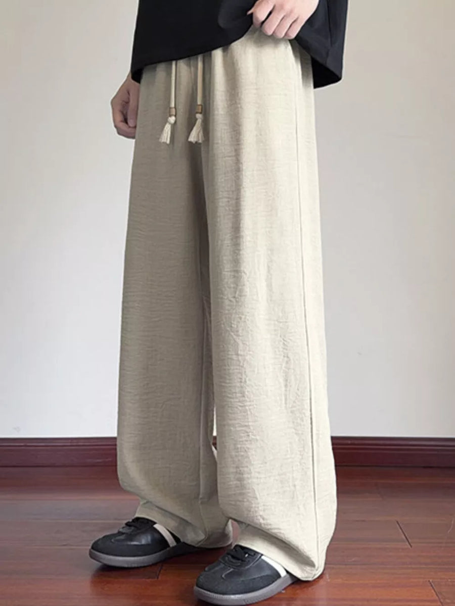 Cream wide-leg drawstring sweatpants with tassel detail and relaxed fit.