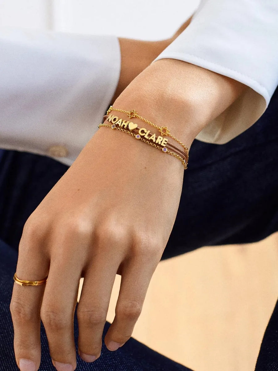 Gold charm bracelets with names Noah and Clare, heart, and star charms