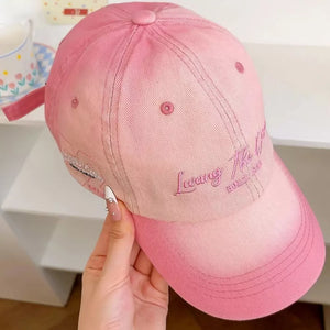Blush pink cotton baseball cap with embroidered text and detail on the side.