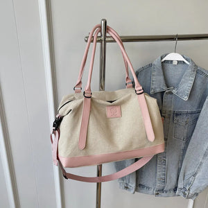 Canvas weekend holdall duffel bag in beige with pink accents and straps.