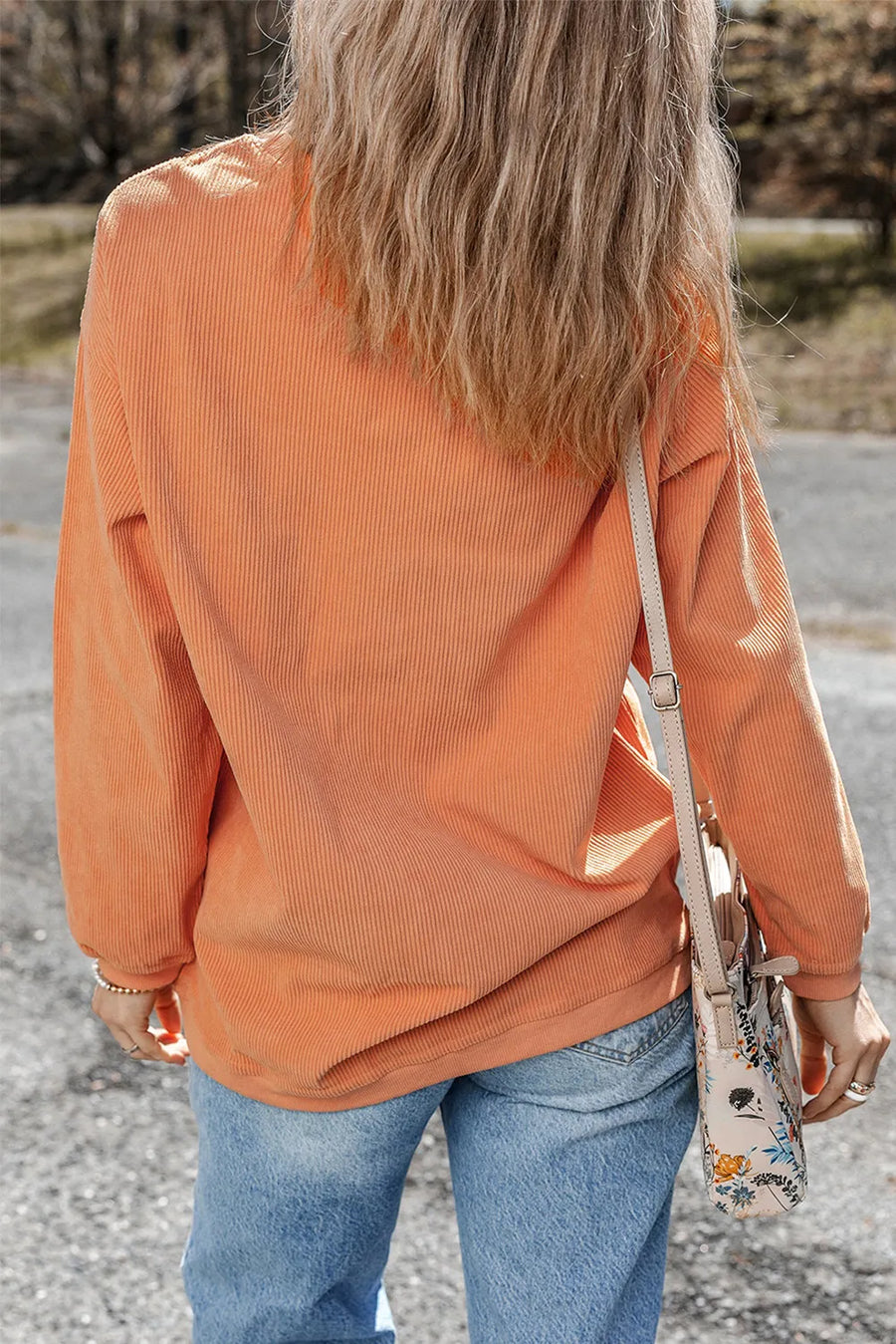 Corduroy sweatshirt in sherbet orange with a relaxed fit, styled with jeans.