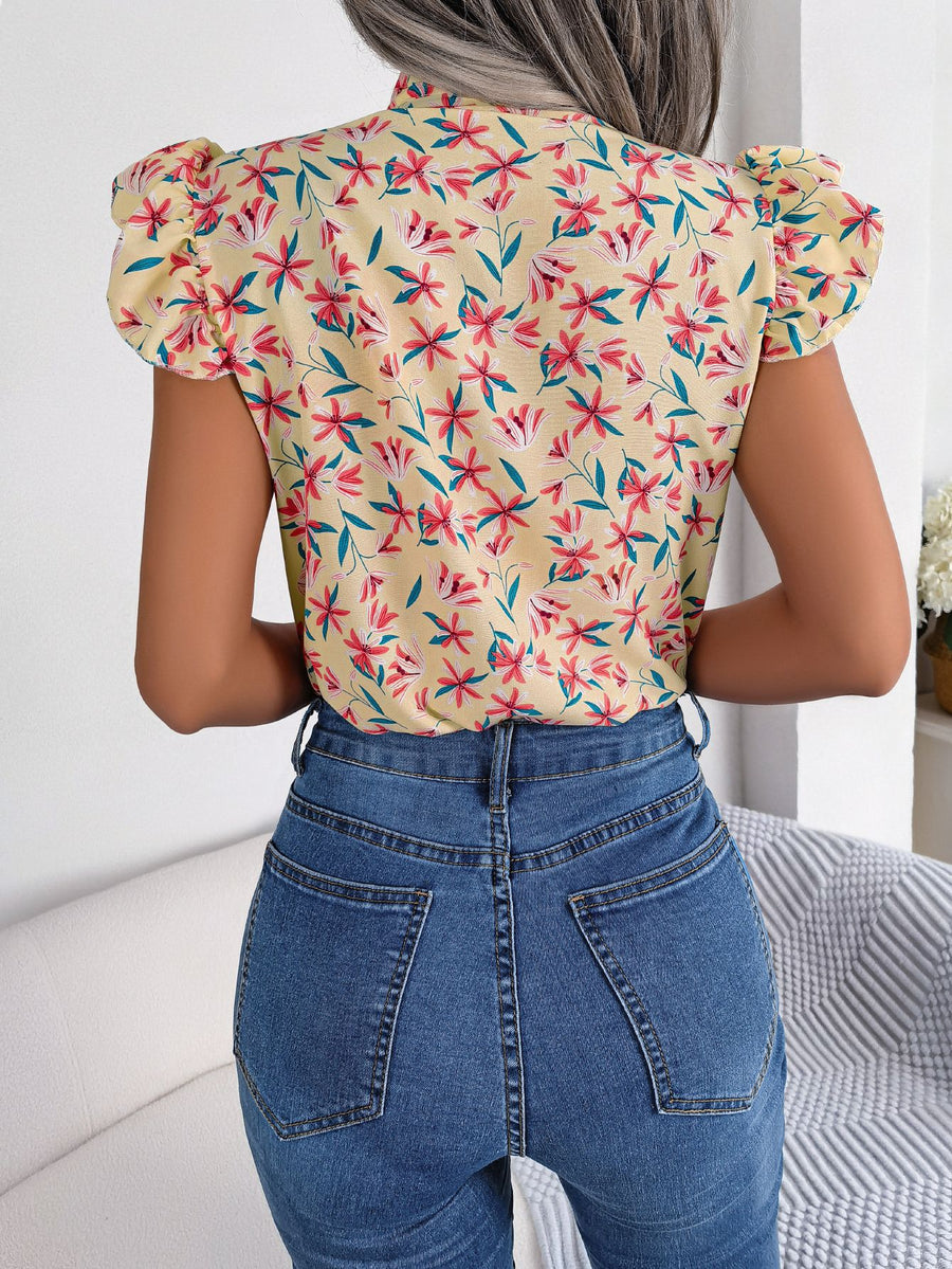 Apricot floral blouse with ruffle sleeves and mock neck, paired with blue denim jeans.