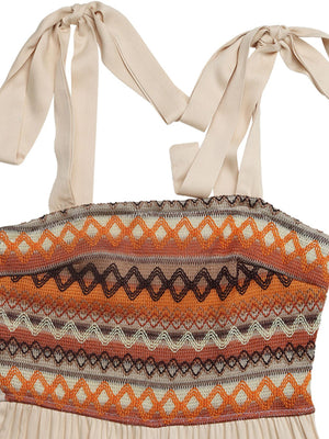 Smocked tie shoulder romper in apricot with geometric pattern and wide legs.
