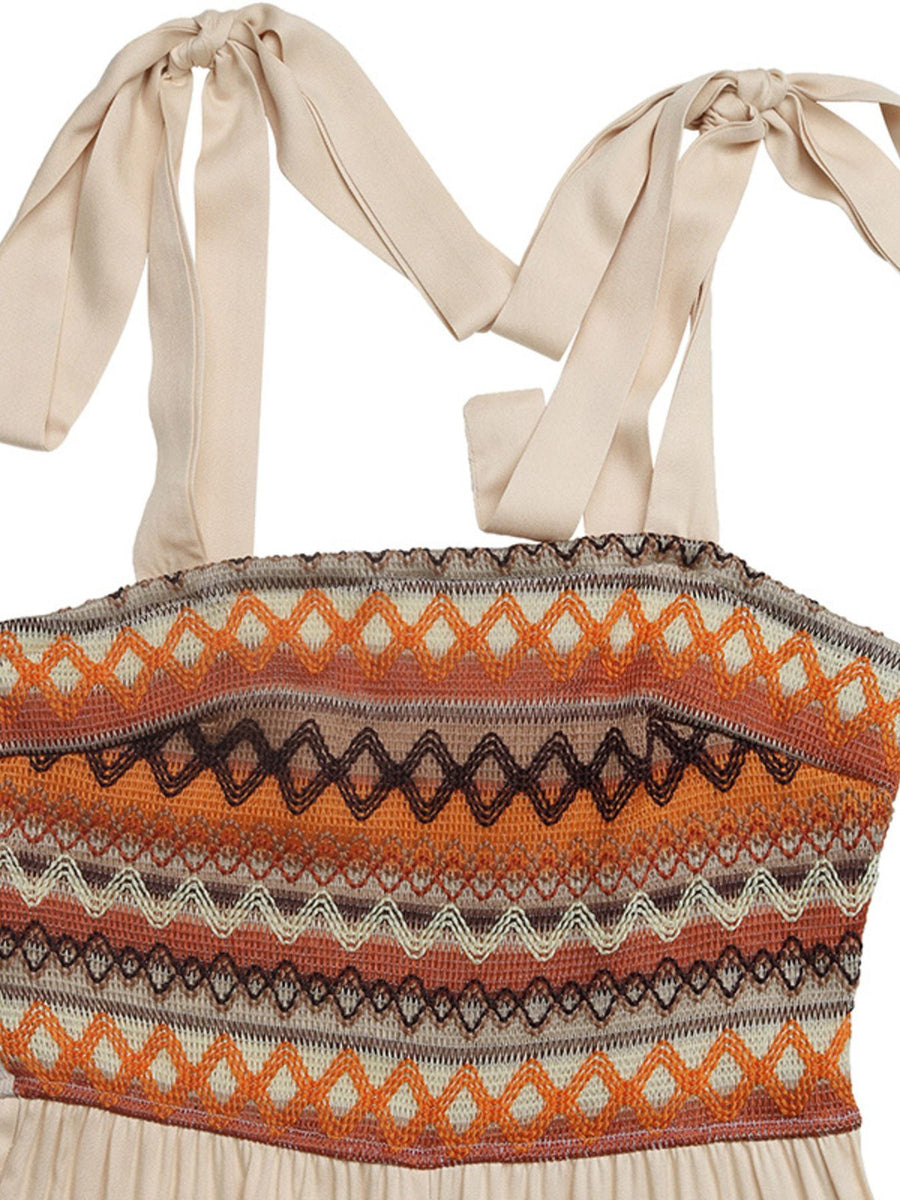 Smocked tie shoulder romper in apricot with geometric pattern and wide legs.