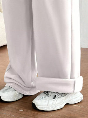 White wide-leg lounge pants with cuffed hems, styled with sneakers.