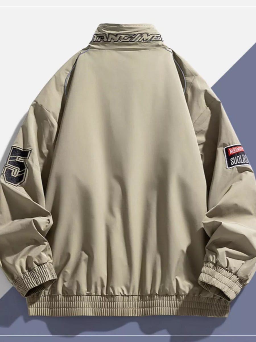 Beige bomber jacket with embroidered patches and text on collar