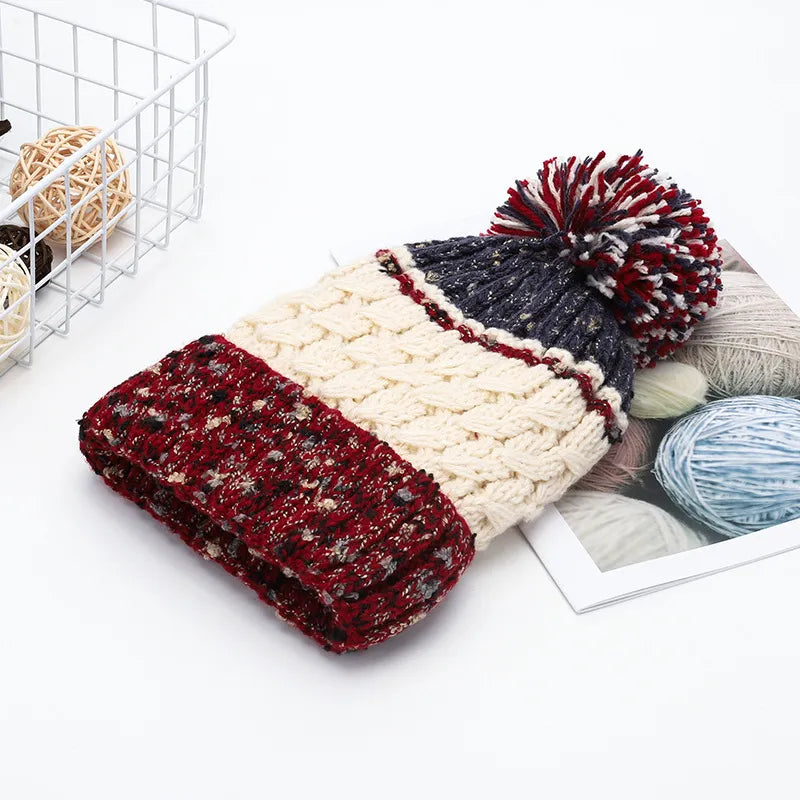 Textured cable knit beanie with a multicolor pompom and red, cream, and navy sections.