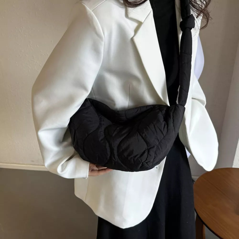 Black puffy quilted crossbody bag with abstract pattern and knotted strap.