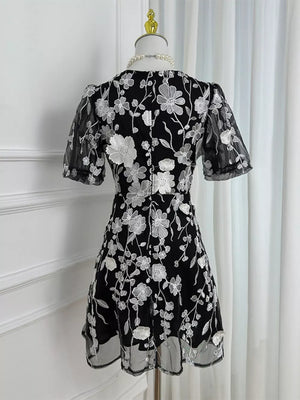 Black floral embroidered mesh dress with short puff sleeves and a flared hem.