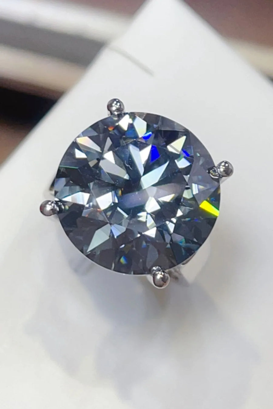 Round moissanite cocktail ring with prong setting, showing blue and yellow flashes.