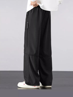 Men's black loose fit cargo pants with zippered pocket detail.