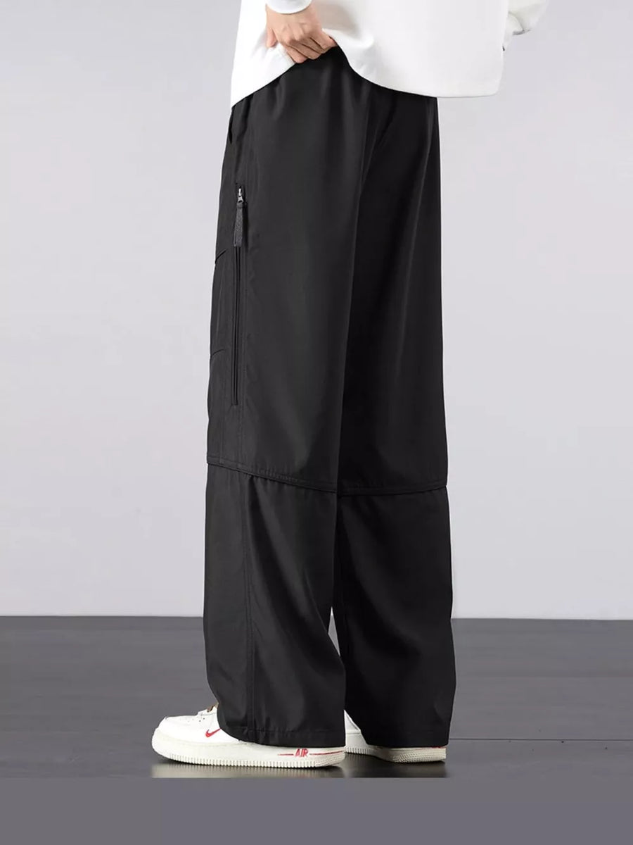 Men's black loose fit cargo pants with zippered pocket detail.