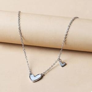 Silver chain necklace with two white heart pendants, one larger than the other.