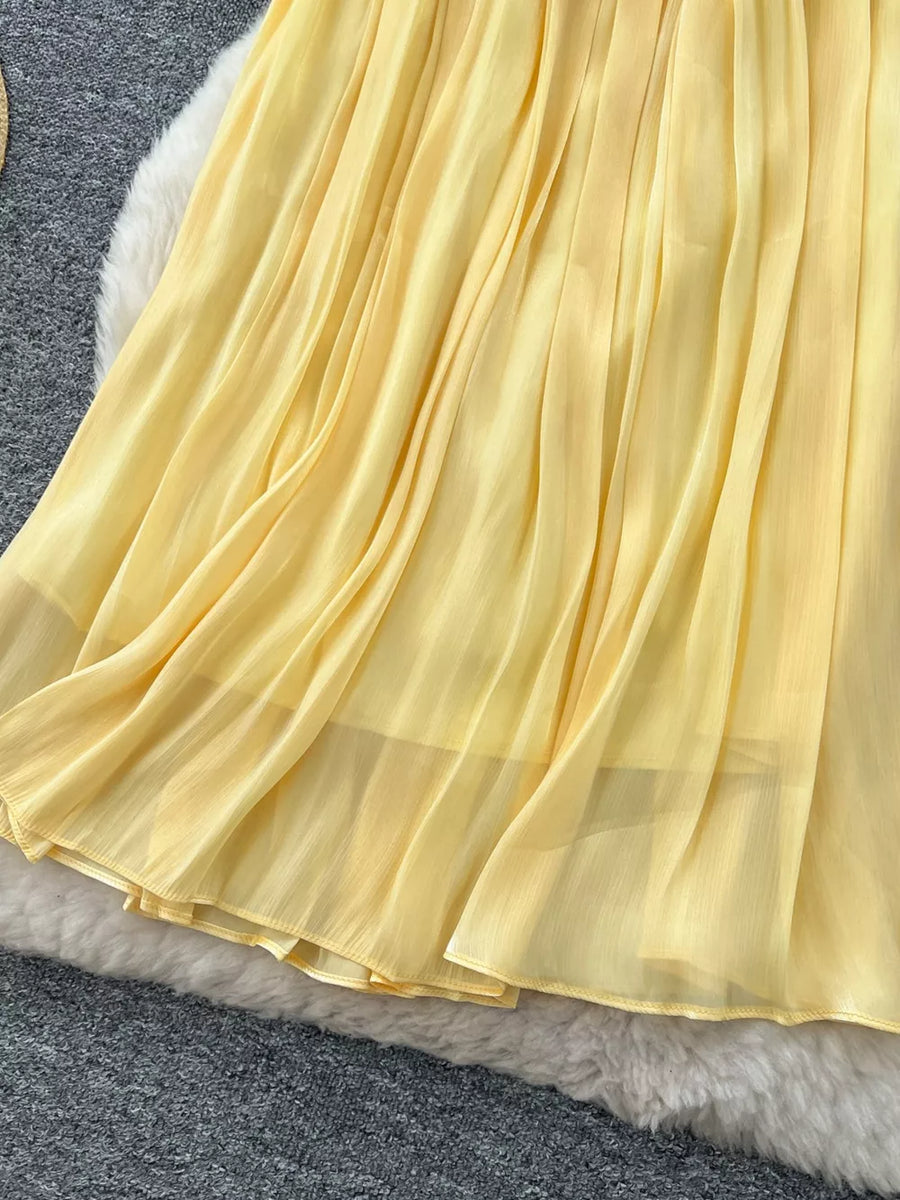 Yellow pleated maxi skirt with flowing chiffon fabric and a delicate hem.