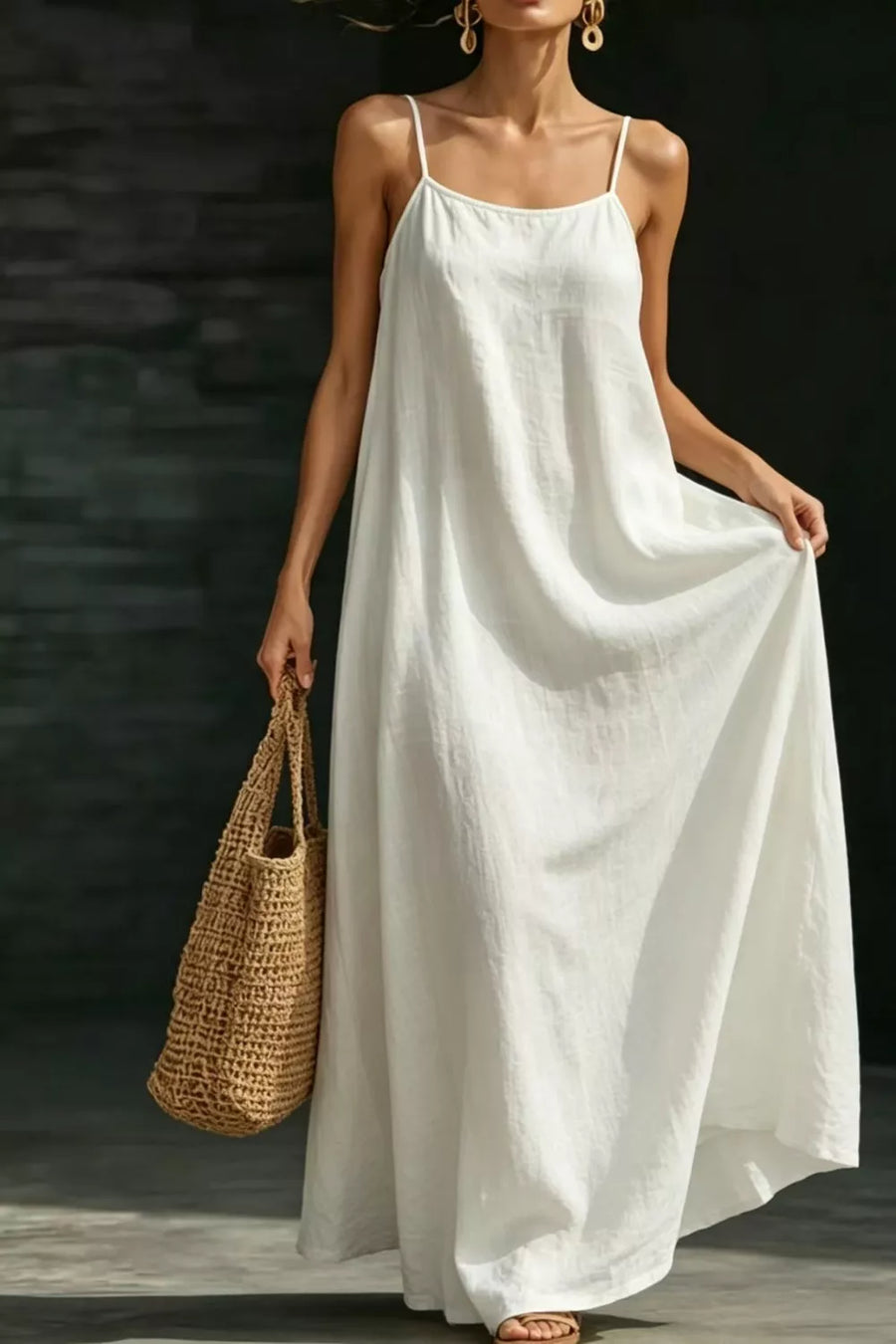 White A-line maxi dress with spaghetti straps and pockets, styled with a straw tote bag.