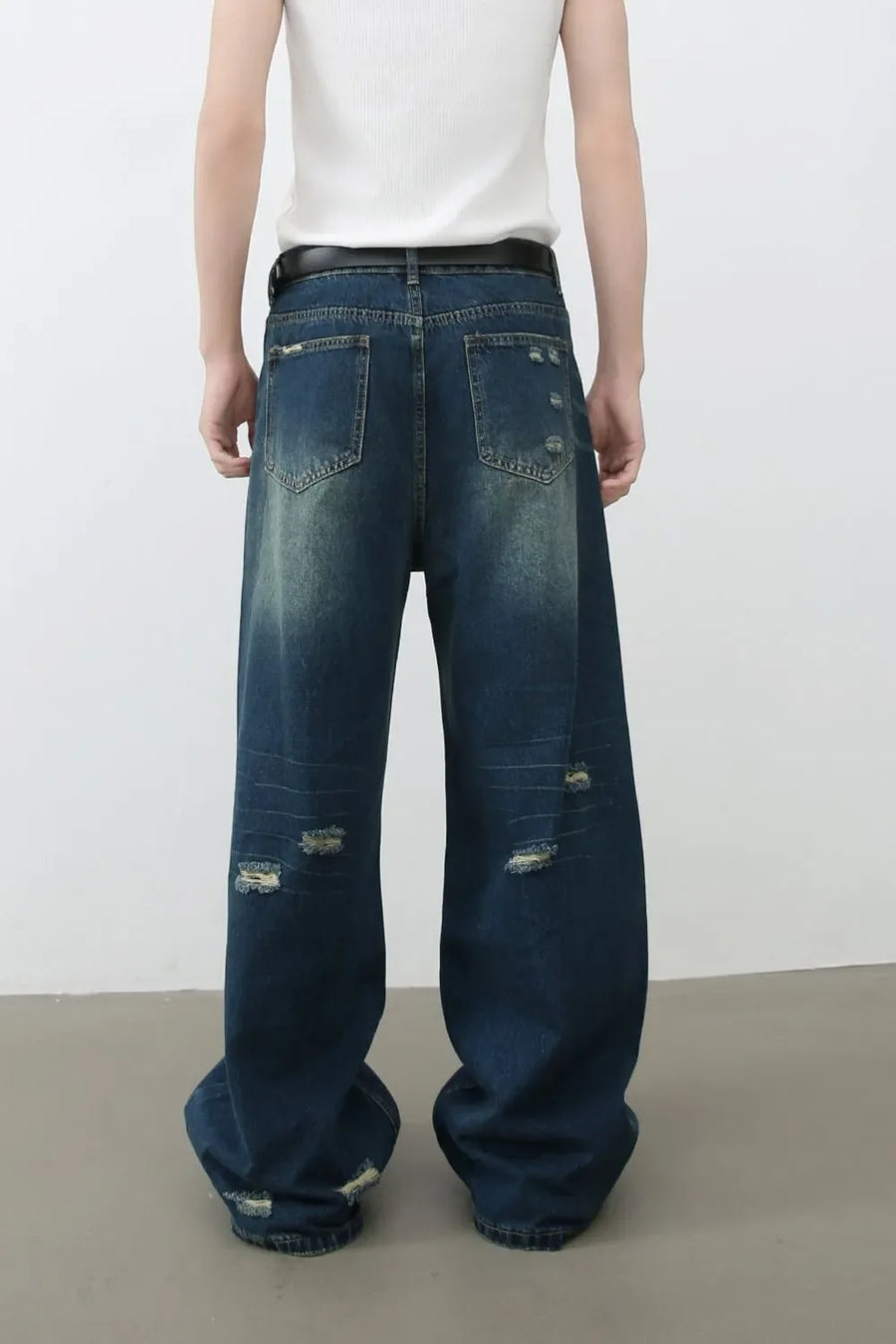 Distressed baggy denim jeans in dark wash with ripped details and a relaxed fit.