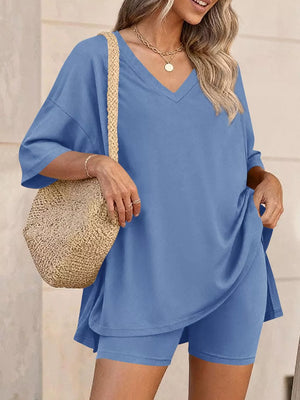 Blue V-neck two-piece set with loose fit top and bike shorts, styled with a straw bag.