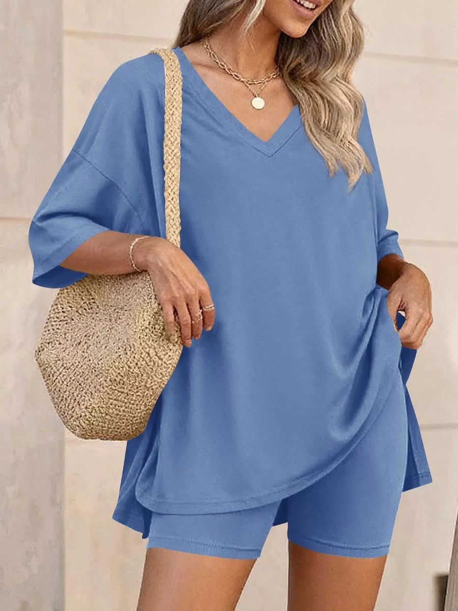 Blue V-neck two-piece set with loose fit top and bike shorts, styled with a straw bag.
