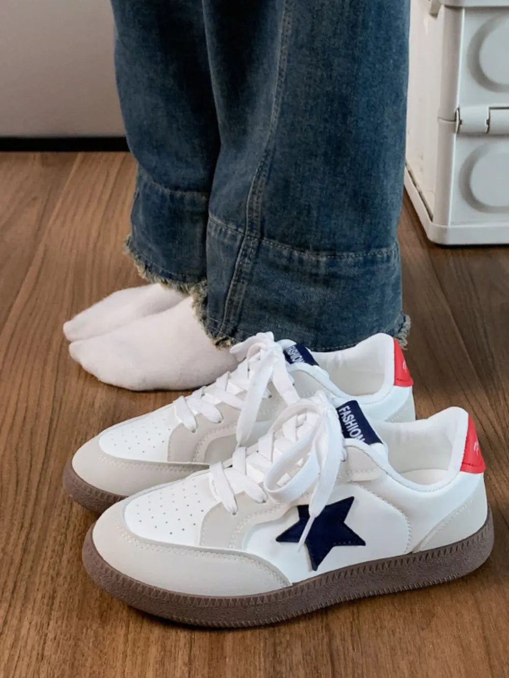 White retro sneakers with navy star appliqué and red heel detail.