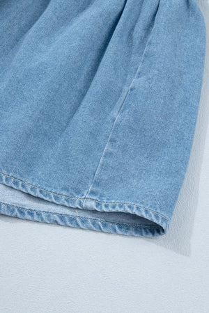Light blue denim dress detail showing ruffled hem and stitching.