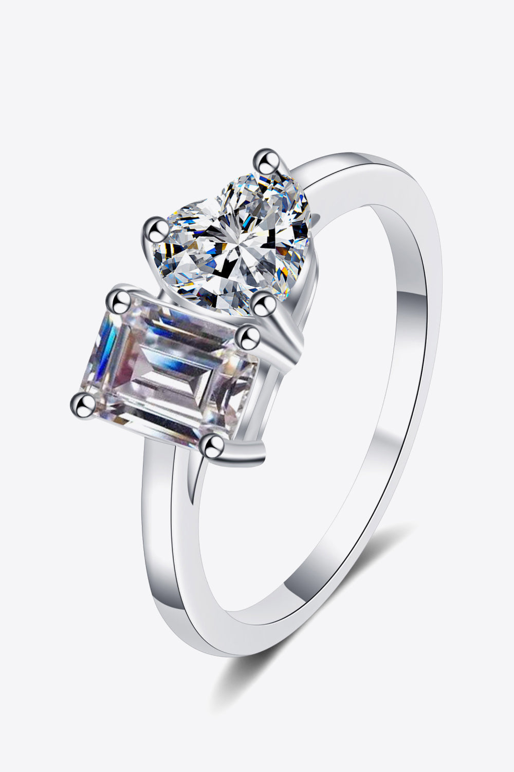 Silver ring with dual-cut moissanite stones: one heart-shaped, one emerald-cut.