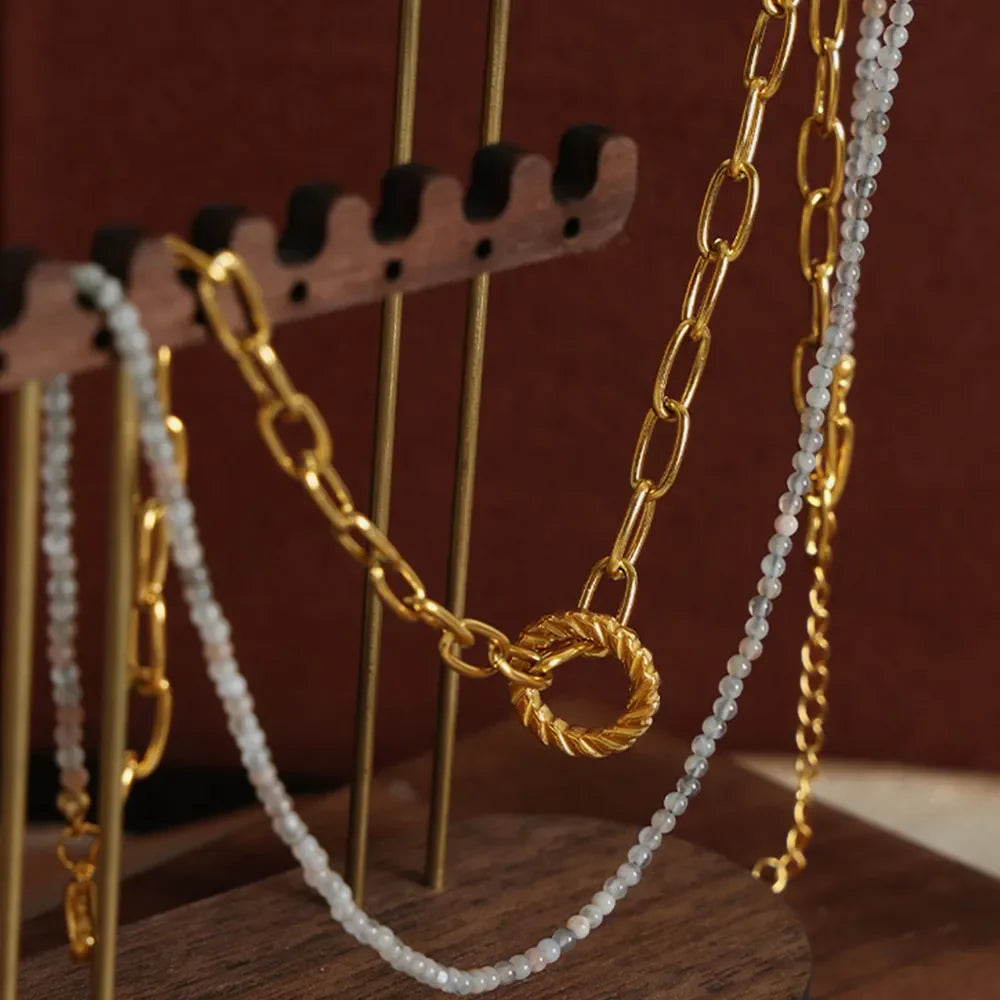 Gold layered chain necklace with beaded pendant and twisted ring clasp.