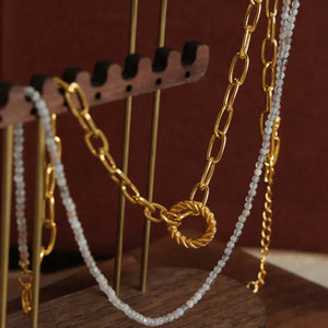 Gold layered chain necklace with beaded pendant and twisted ring clasp.
