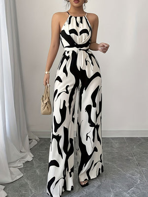 Elegant wide-leg jumpsuit in black and white abstract print with halter neck and tie waist.