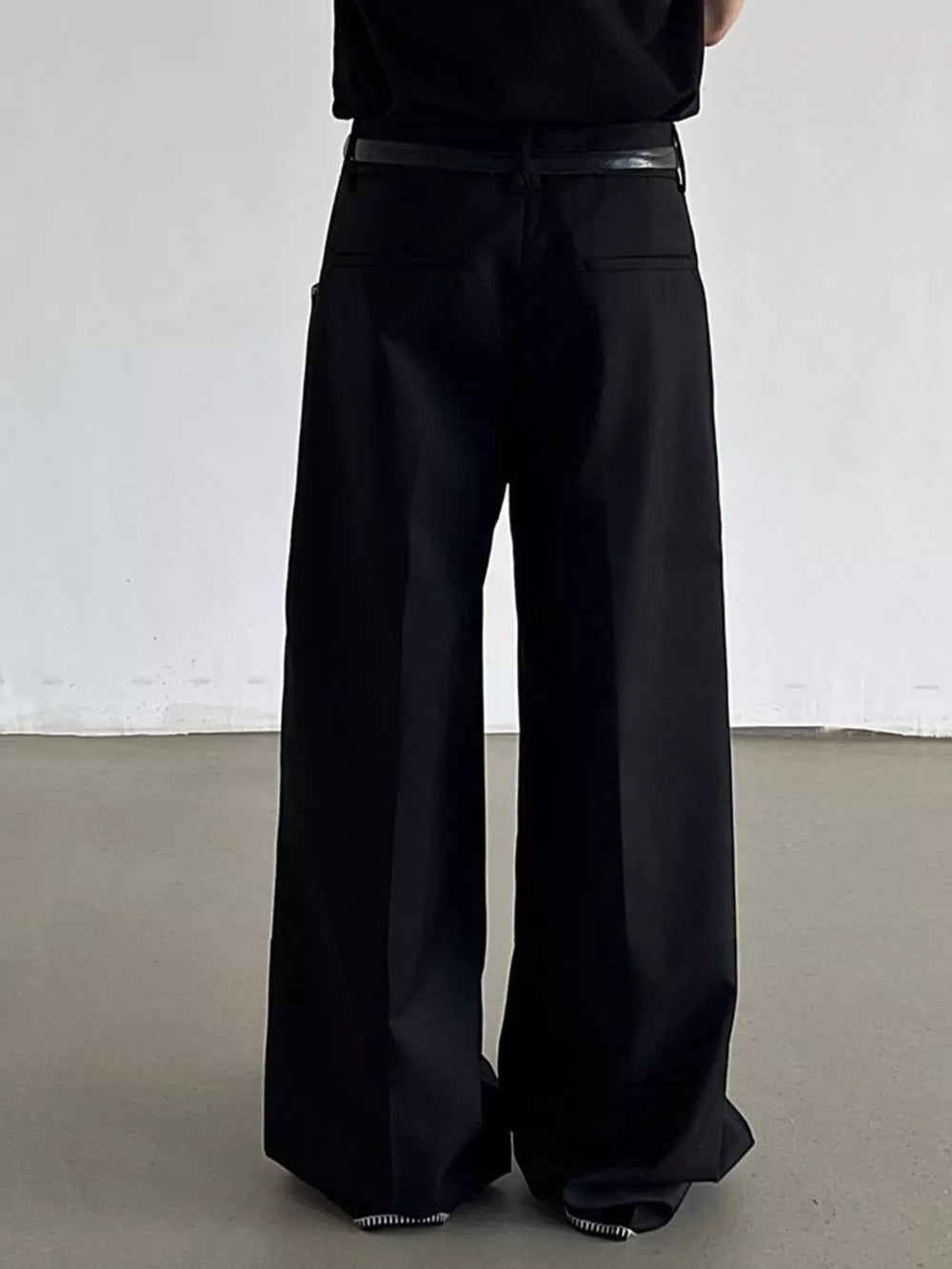 Black relaxed fit wide-leg dress pants with a belt and decorative trim.