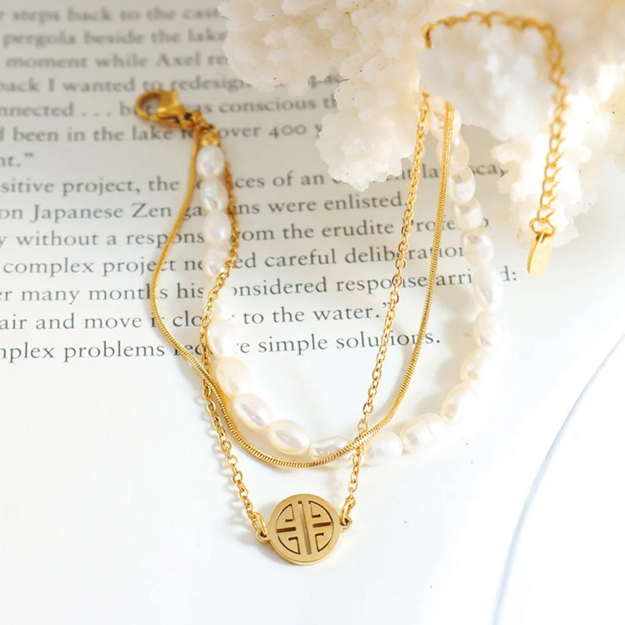 Gold layered bracelet with pearls, chain, and a circular charm.