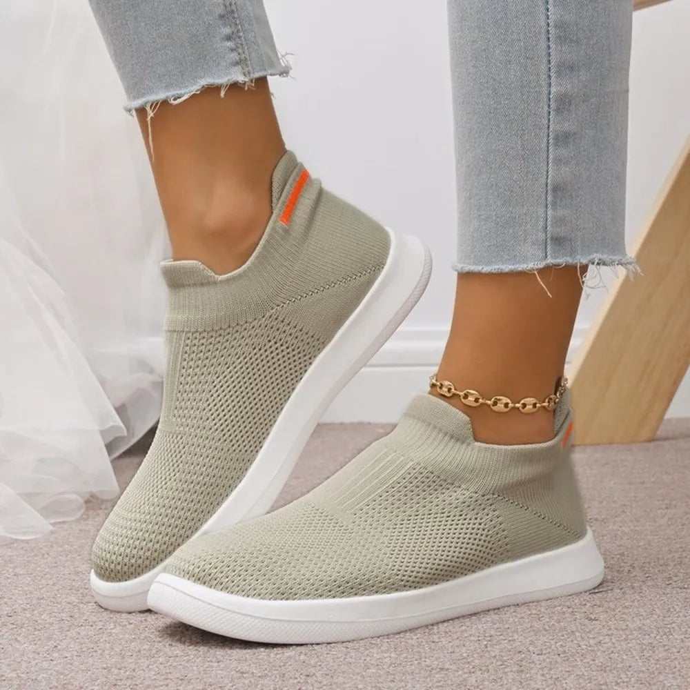 Airy knit slip-on sneakers in light grey with orange accent detail and white soles.