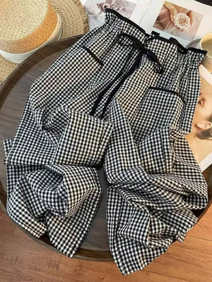 High-waisted wide-leg gingham pants in black and white with a drawstring waist and pockets.