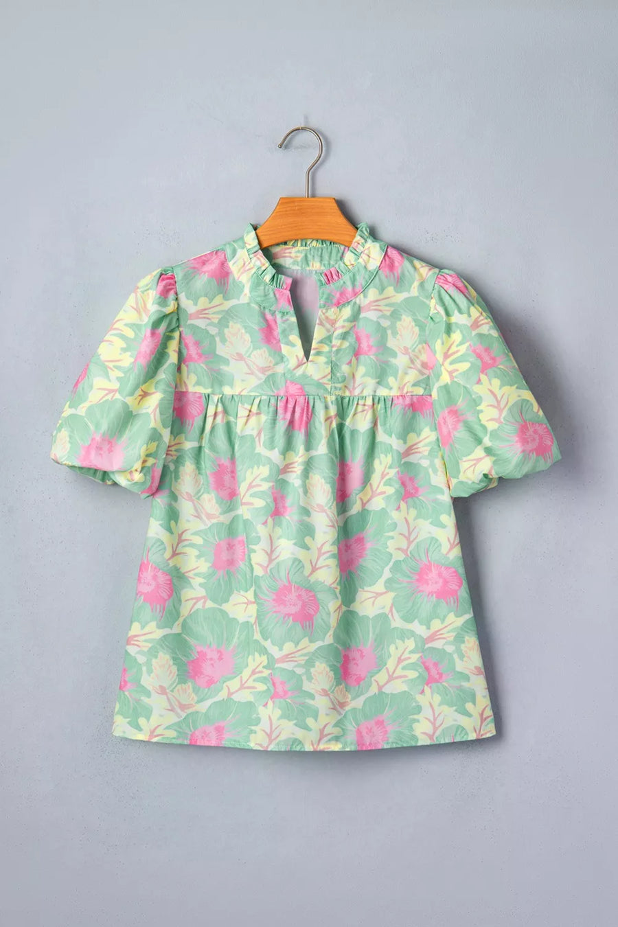 Pastel floral print polyester blouse with ruffled neckline and puff sleeves.