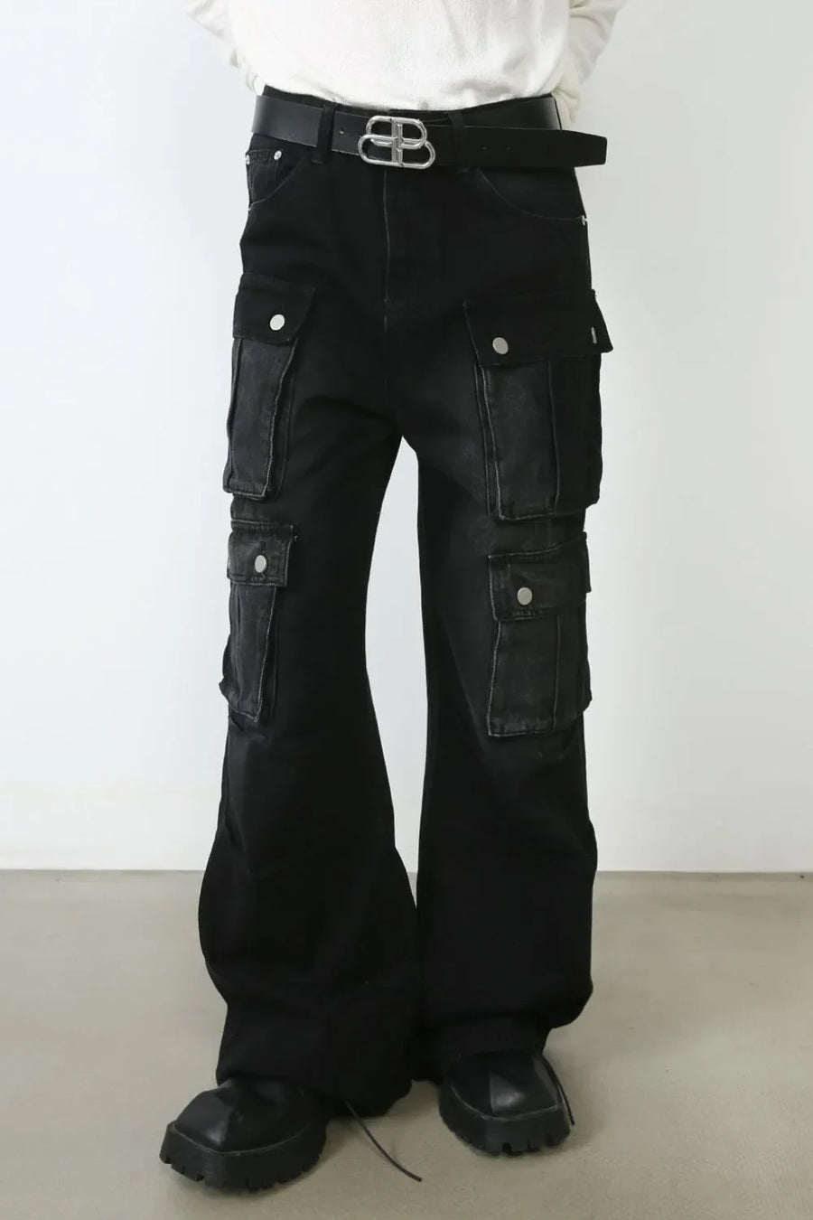 Dark oversized denim cargo pants with multiple pockets and a flared leg.
