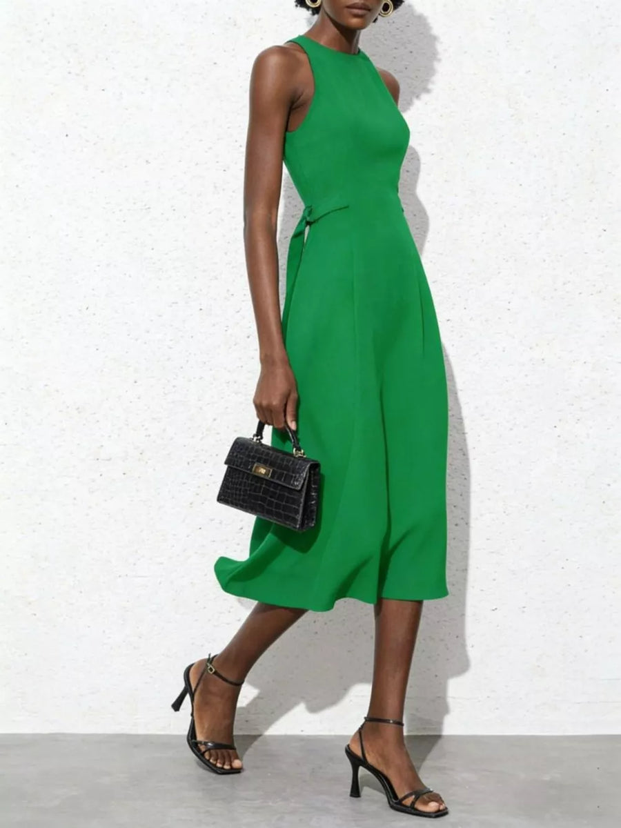 Green midi dress with tie waist, sleeveless, A-line skirt, and a black croc-embossed handbag.