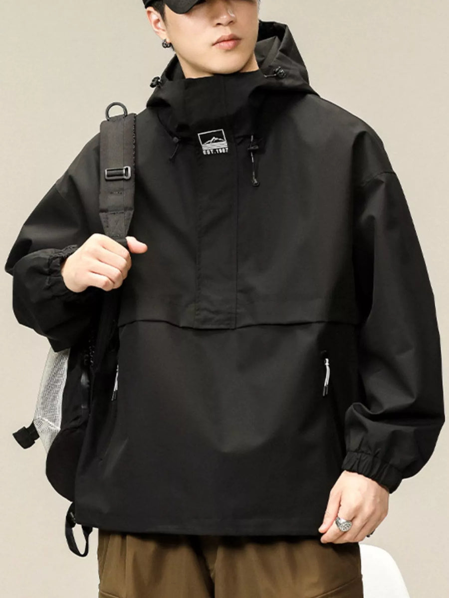 Black oversized hooded windbreaker jacket with chest logo and zippered pockets.