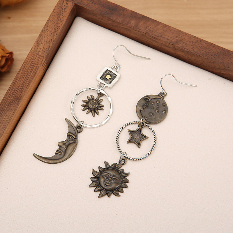 Cosmic asymmetry drop earrings in copper feature sun, moon, and star charms with a bohemian vibe.