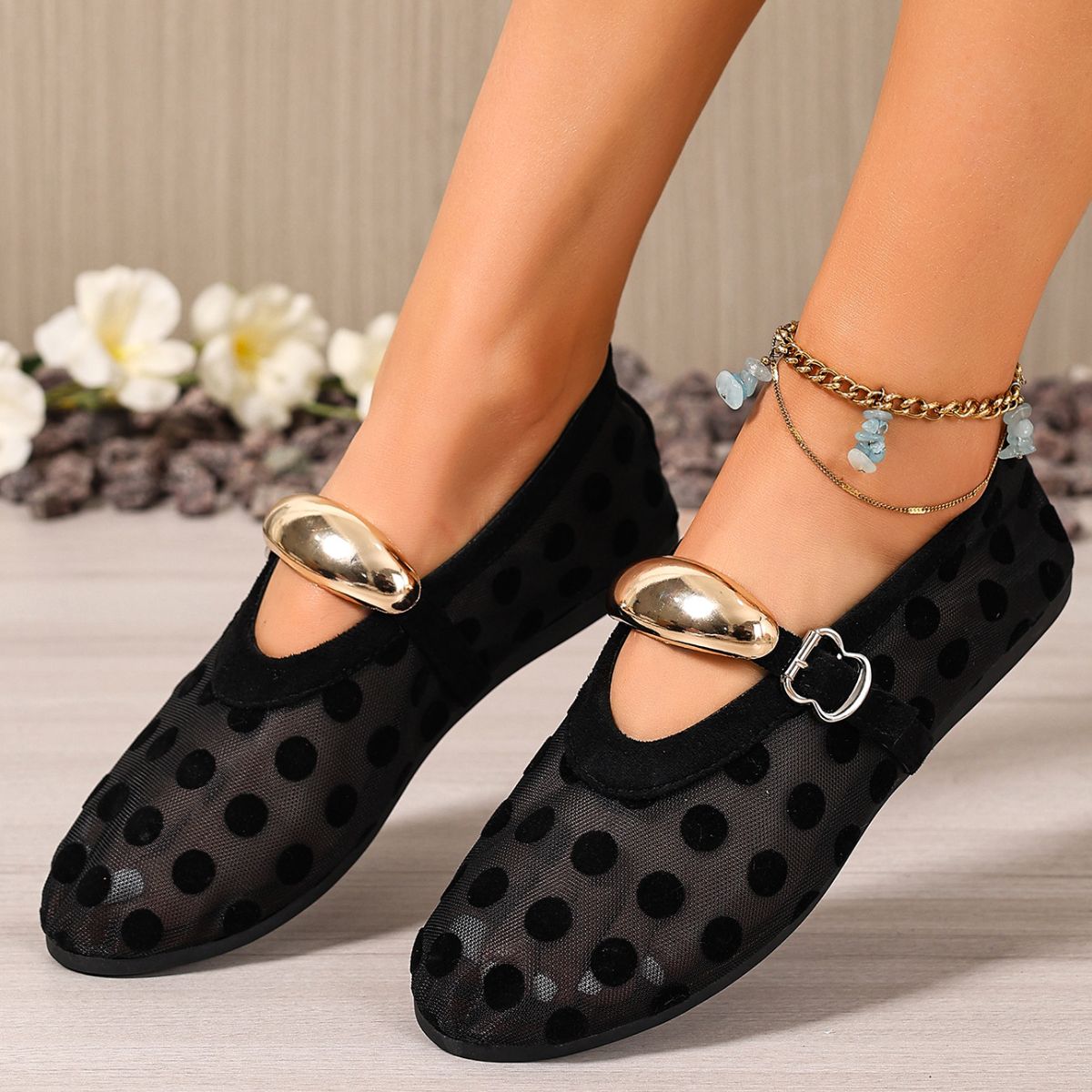 Black polka dot mesh slip-on flats with gold accent and buckle detail.