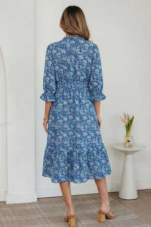 Blue floral cotton midi dress with cinched waist, frilled cuffs and tiered hem.