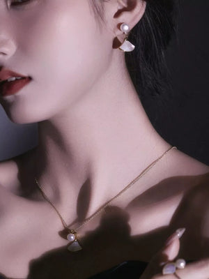 Elegant fan-shaped pearl earrings with white shell accents and a delicate gold chain necklace.