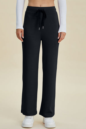 Black wide leg lounge pants with drawstring waist and white sneakers