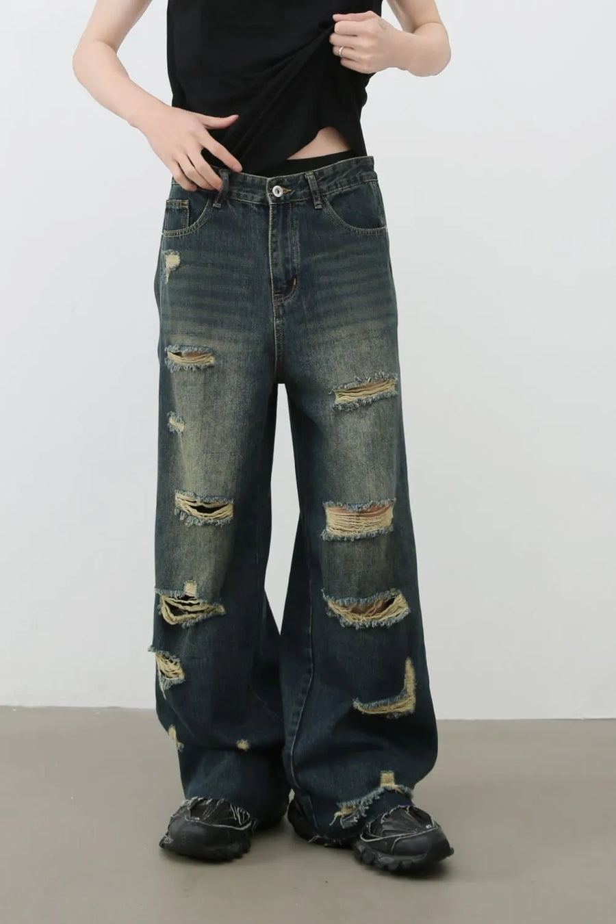 Distressed dark wide leg denim jeans with ripped details and side slits.