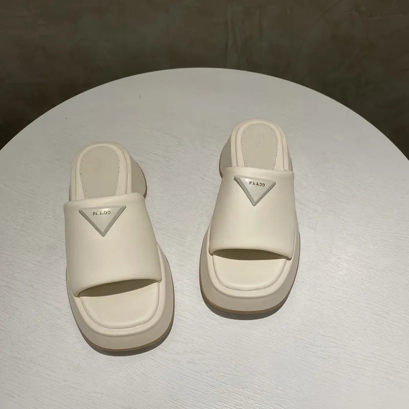 Ivory geometric platform slides with branding detail and open toe.