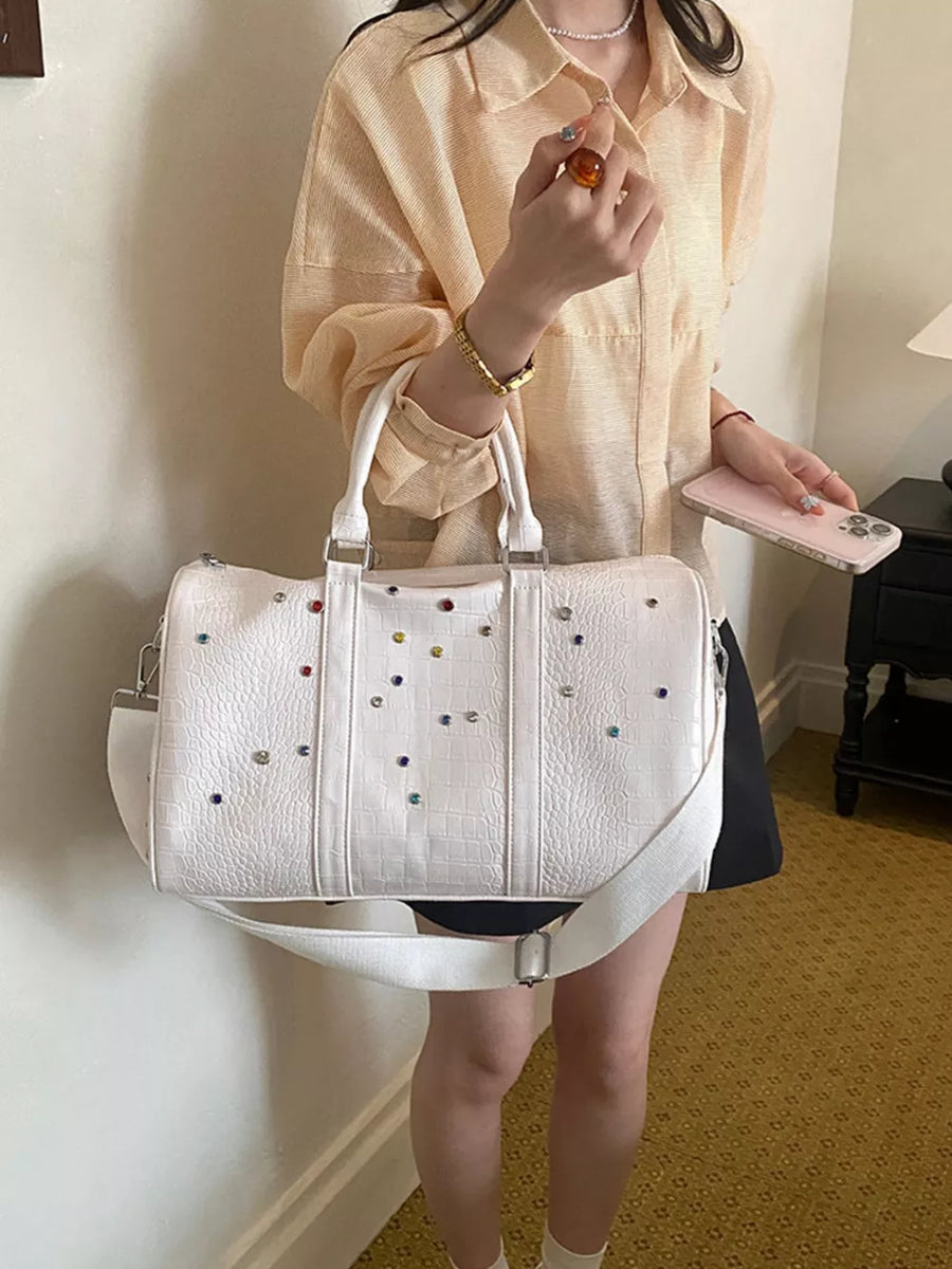 White crocodile textured duffel bag with colorful studs and detachable strap